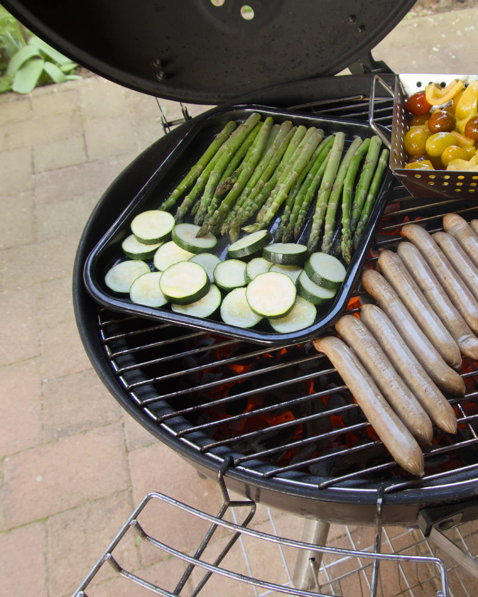 BBQ grill with sausages, asparagus, zucchini, and cherry tomatoes
