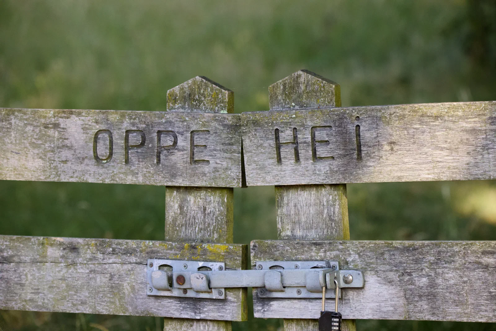Weathered wooden gate with Oppe Hei carved into it