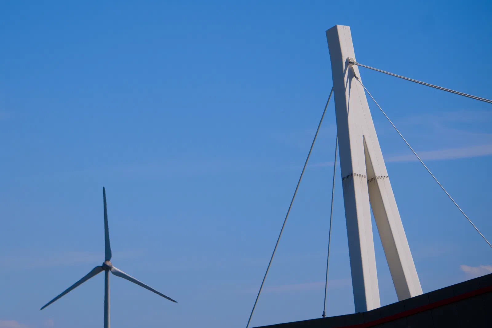 Wind turbine and white canopy mast against blue sky