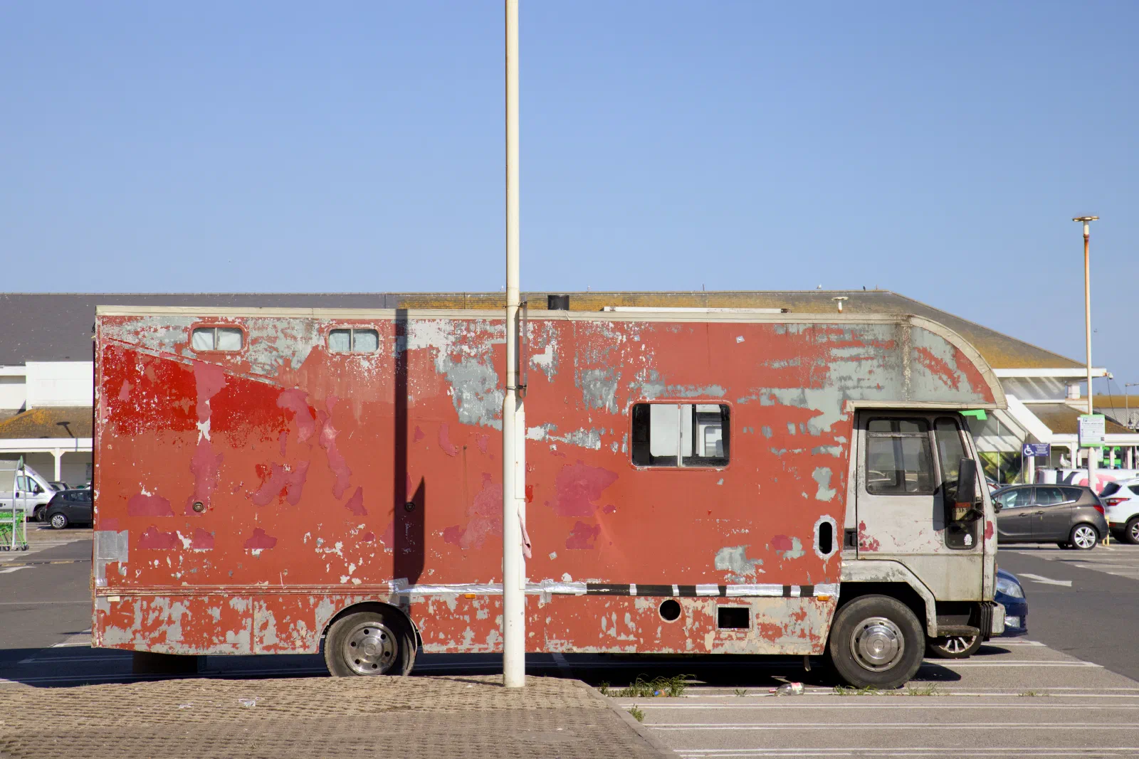 Weathered red horsebox camper in a supermarket car park