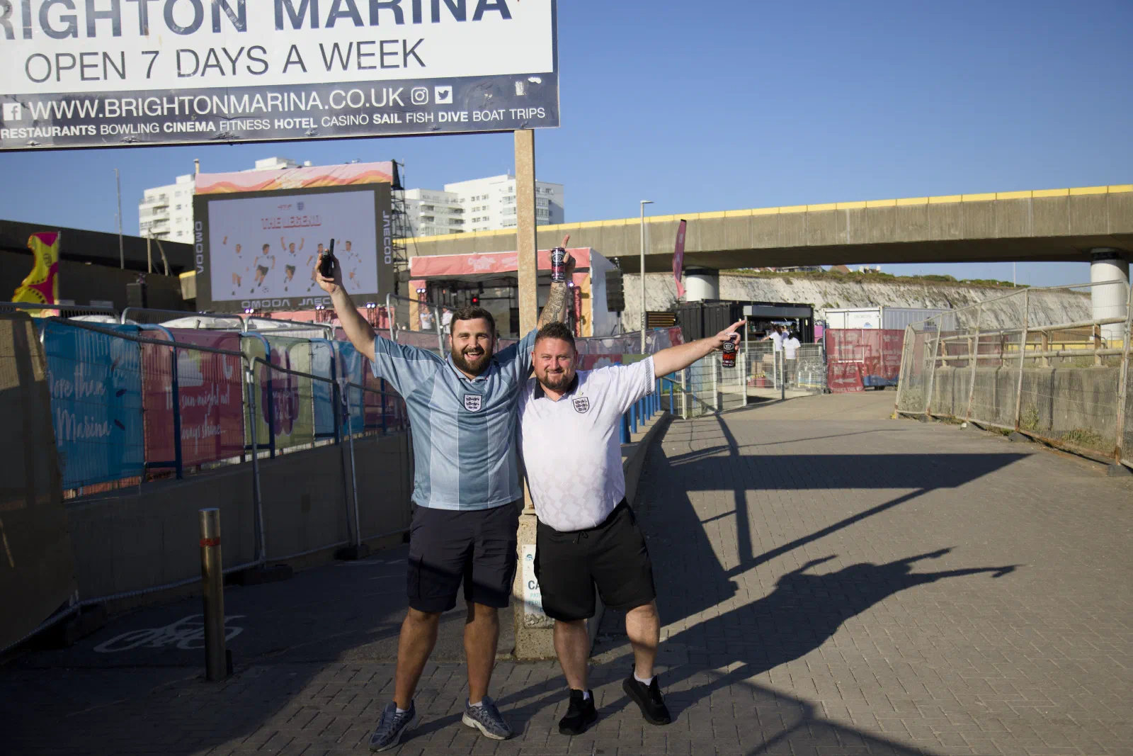 Two England fans posing under the Brighton Marina sign