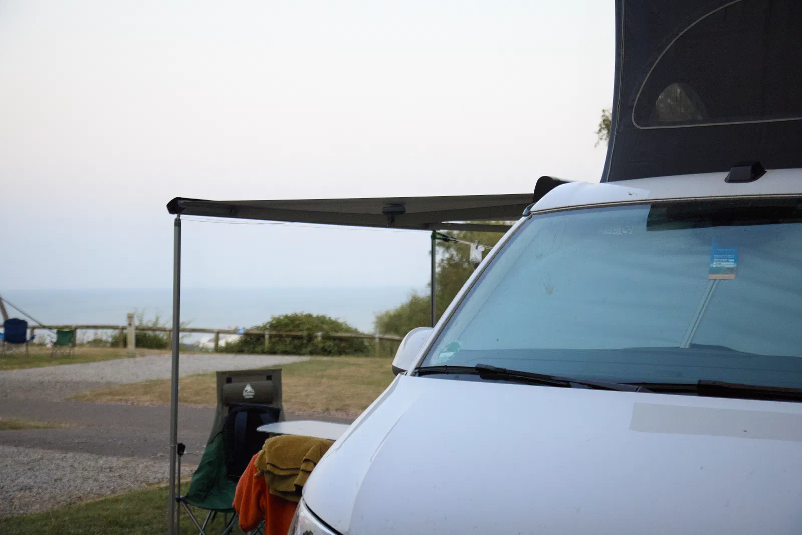 California with the roof up and the awning out, the sea in the background