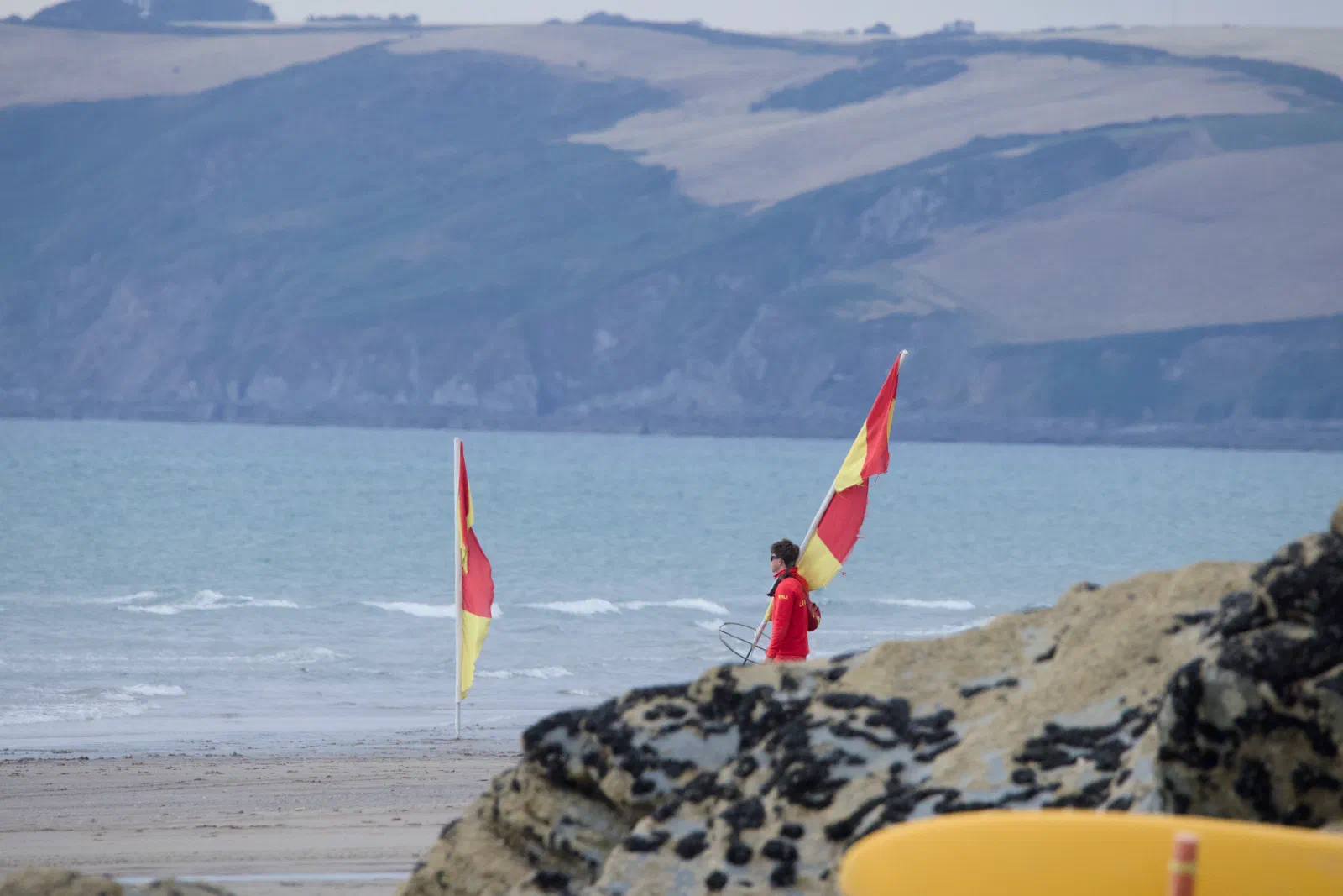 Lifeguard carrying the red and yellow flags off the beach