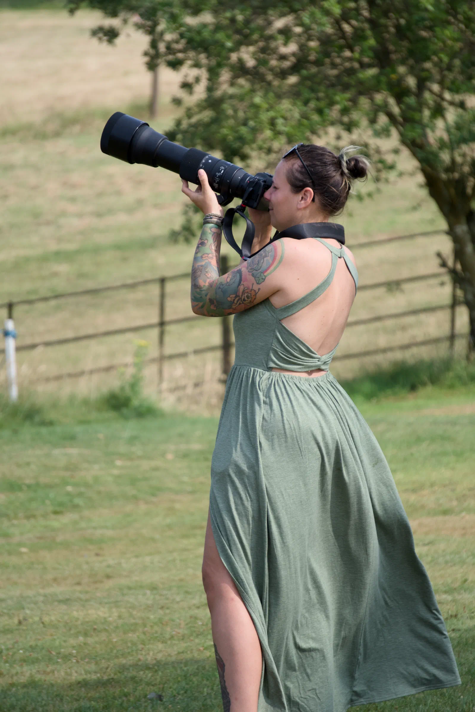 Nadine in a green dress aiming a long telephoto lens
