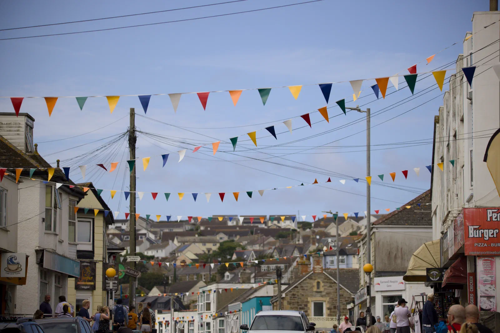 Bunting strung across the main street of Perranporth, houses on the hillside behind