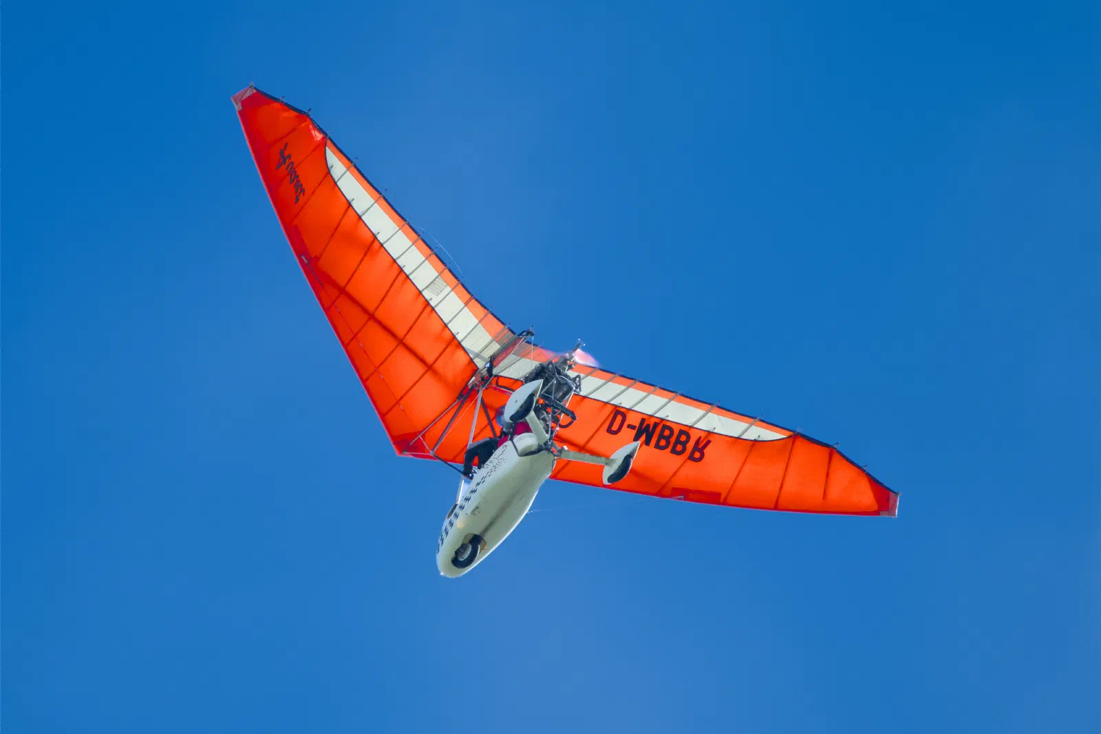 Orange microlight trike against a blue sky