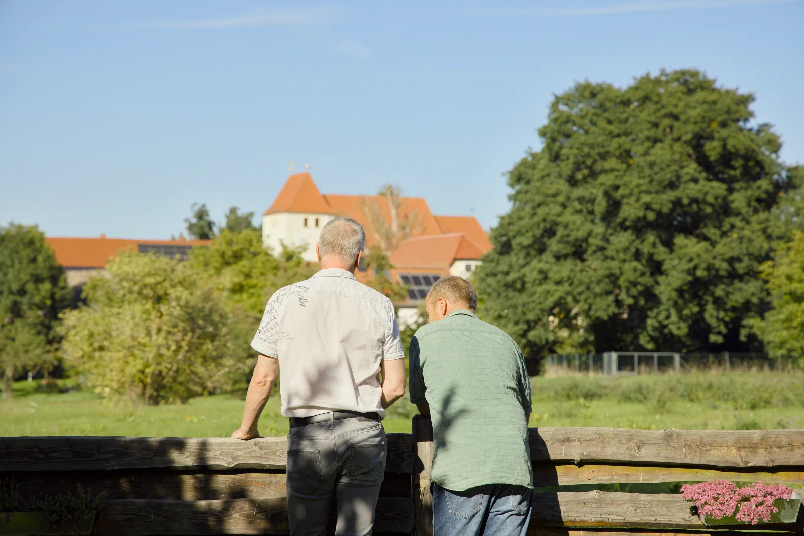 Both fathers leaning on a wooden fence