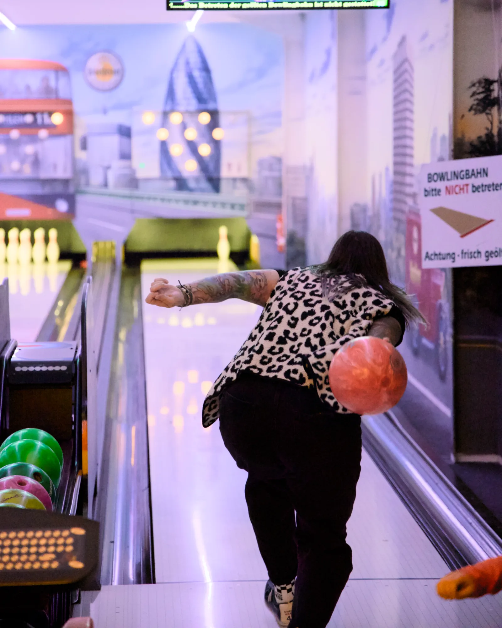 Woman in a leopard print top throwing a bowling ball