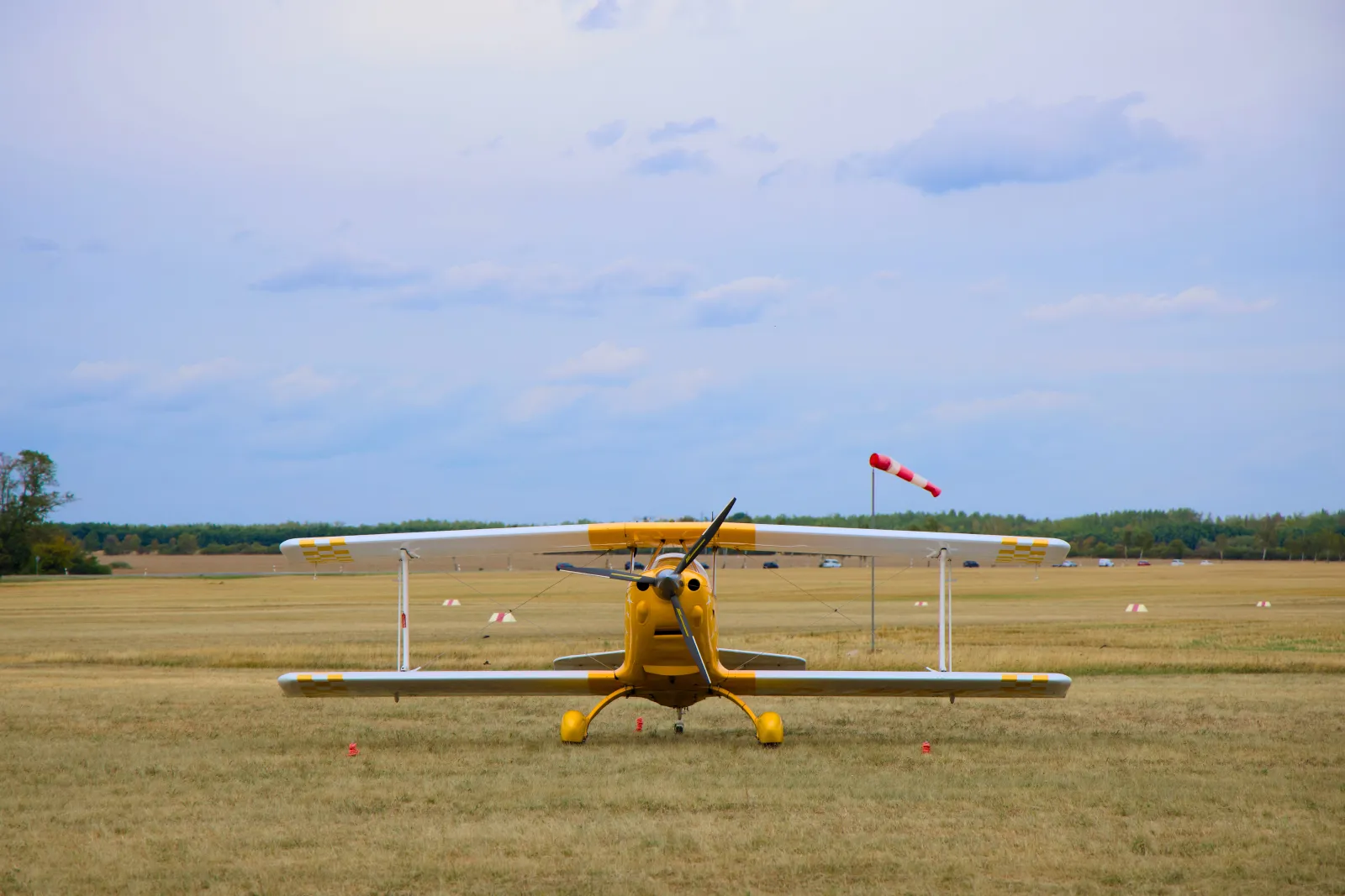 Yellow aerobatic biplane head-on with windsock
