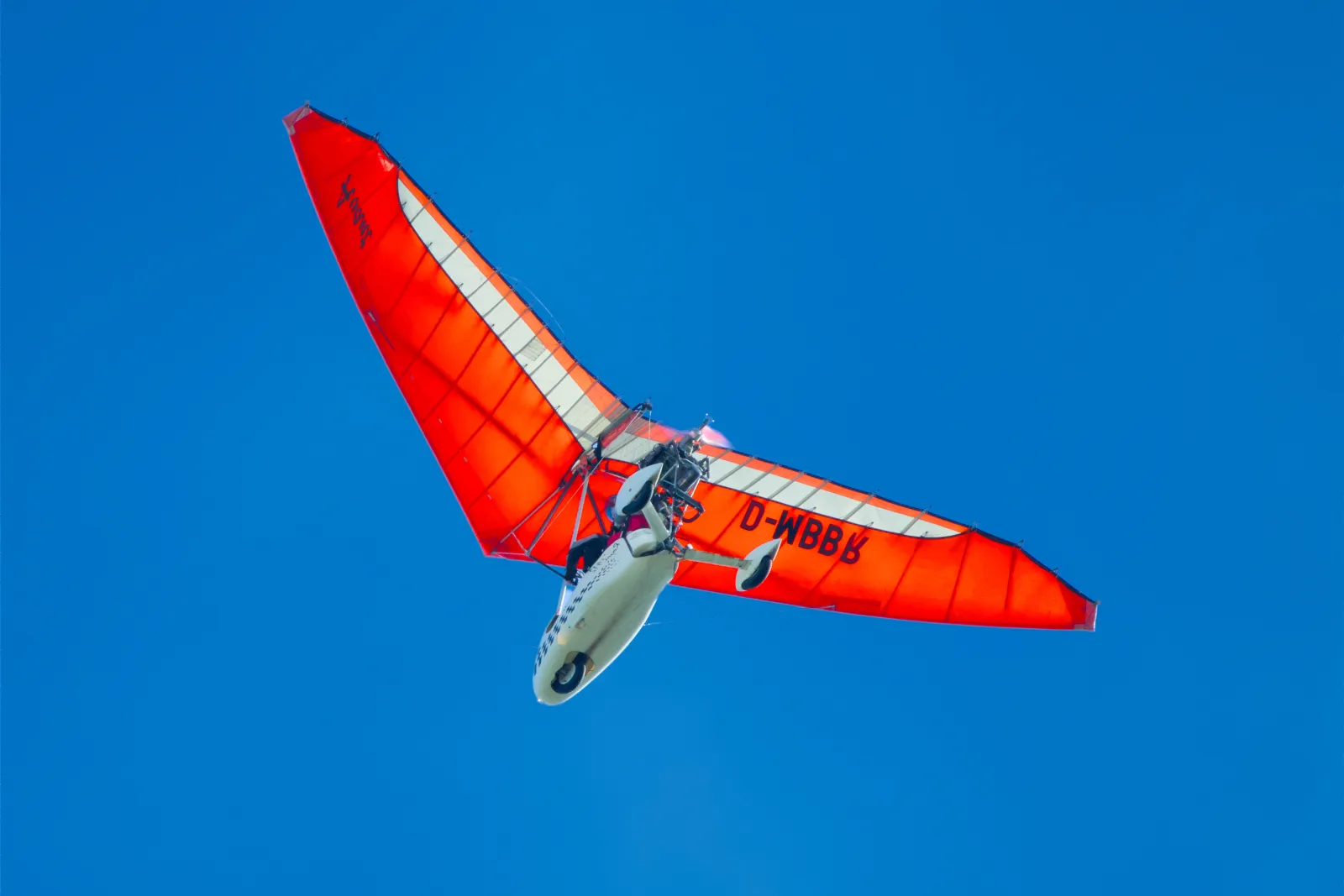 Orange microlight trike against a blue sky