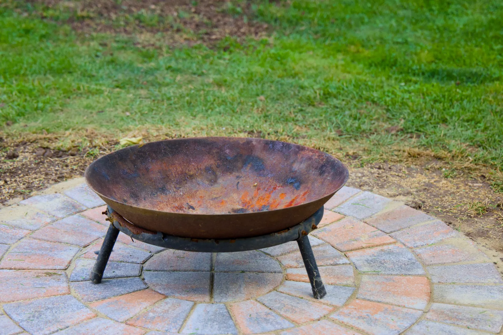 Rusty fire bowl on a paved circle in the lawn