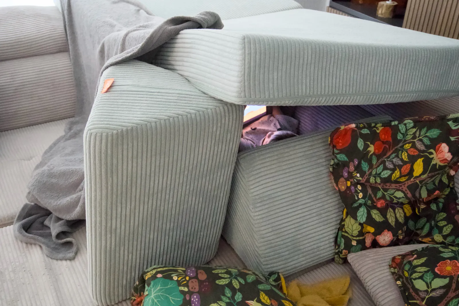 Pillow fort built from couch cushions and floral pillows