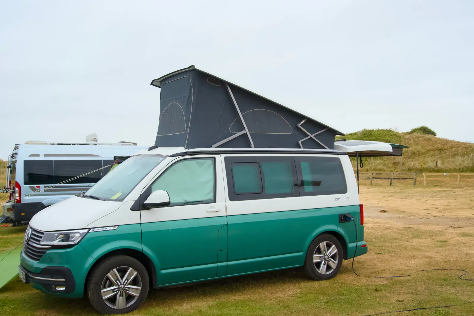 The California with the roof up on the pitch, dunes behind
