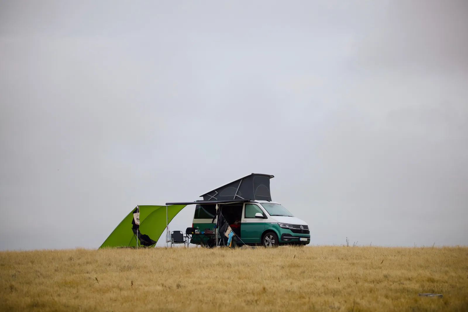 The California with the roof up and a green windbreak on the cliff-top field