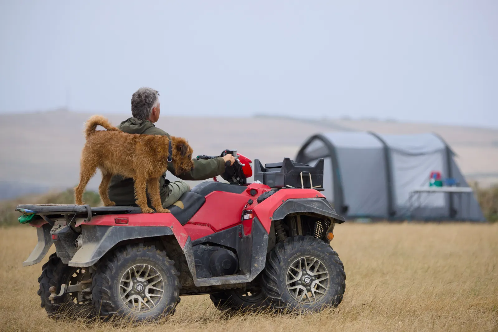 Farmer on a quad bike with a terrier standing on the back