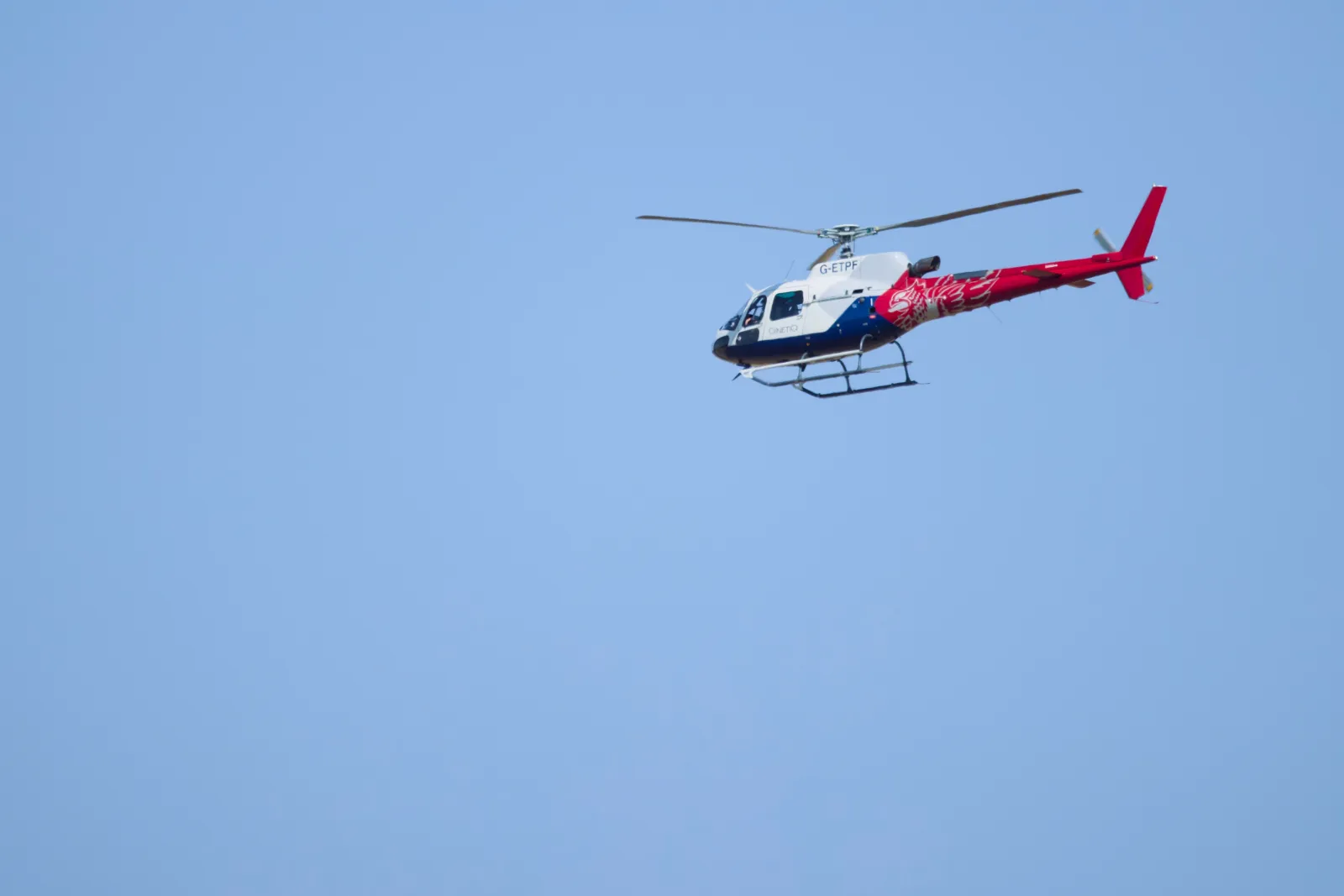 QinetiQ helicopter in flight against a blue sky