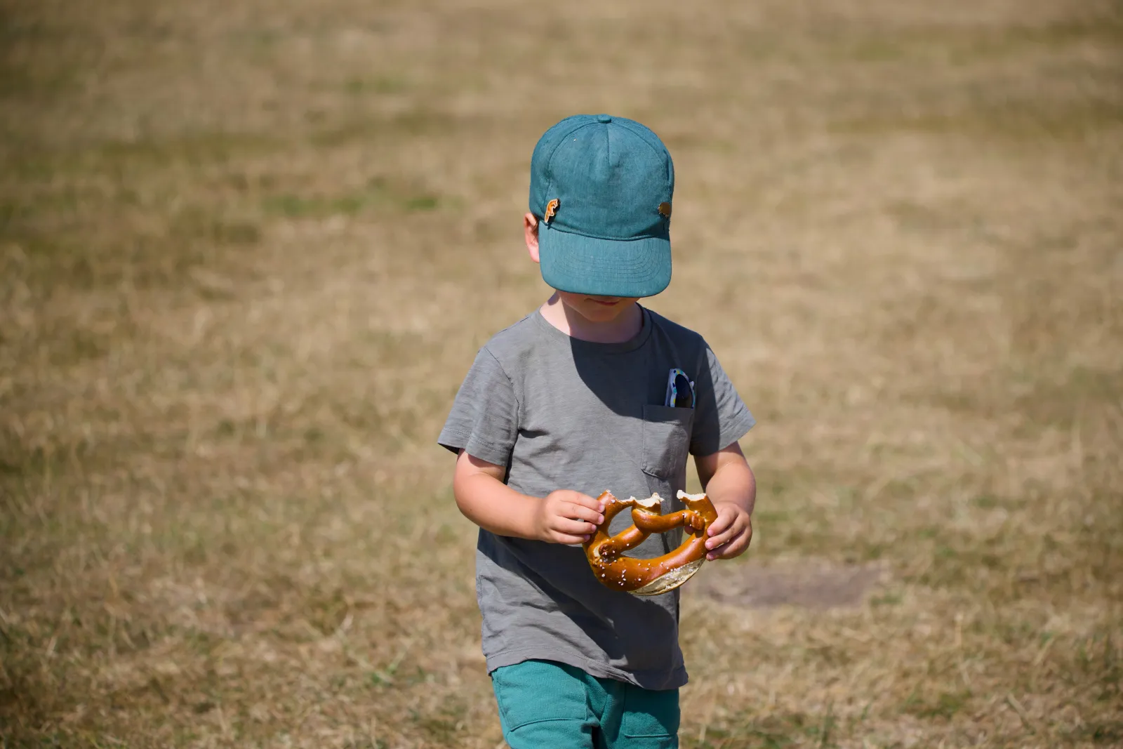 Kellin with a green cap eating a large pretzel