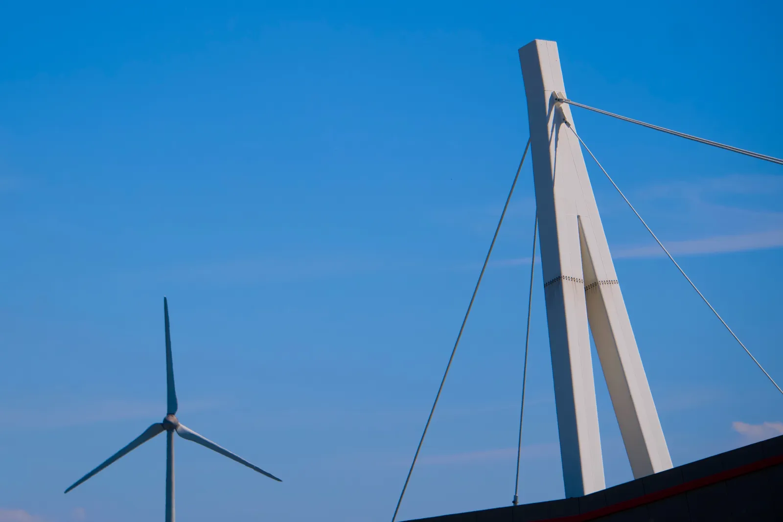 Wind turbine and white canopy mast against blue sky