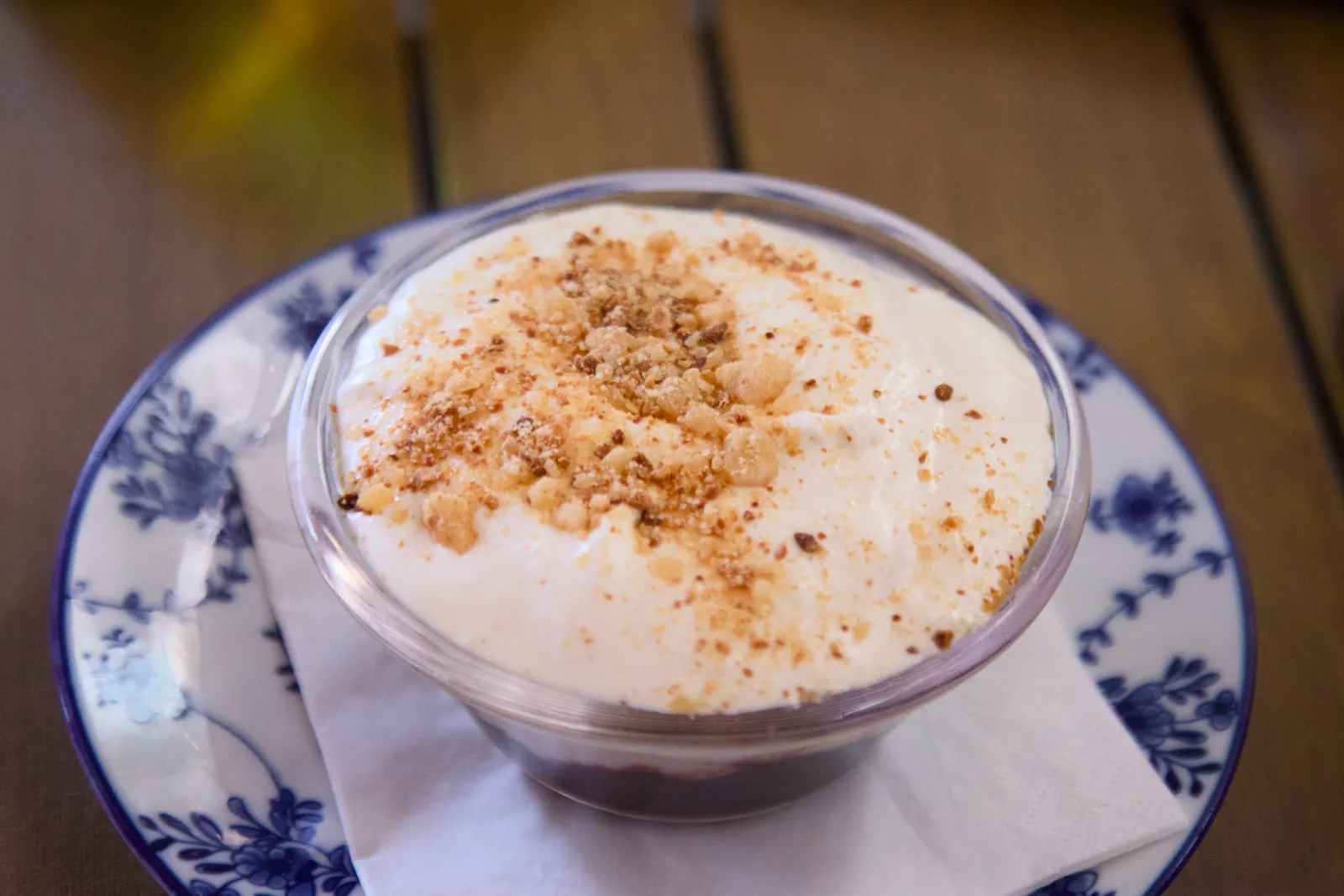 Glass bowl of dessert topped with whipped cream and crumble