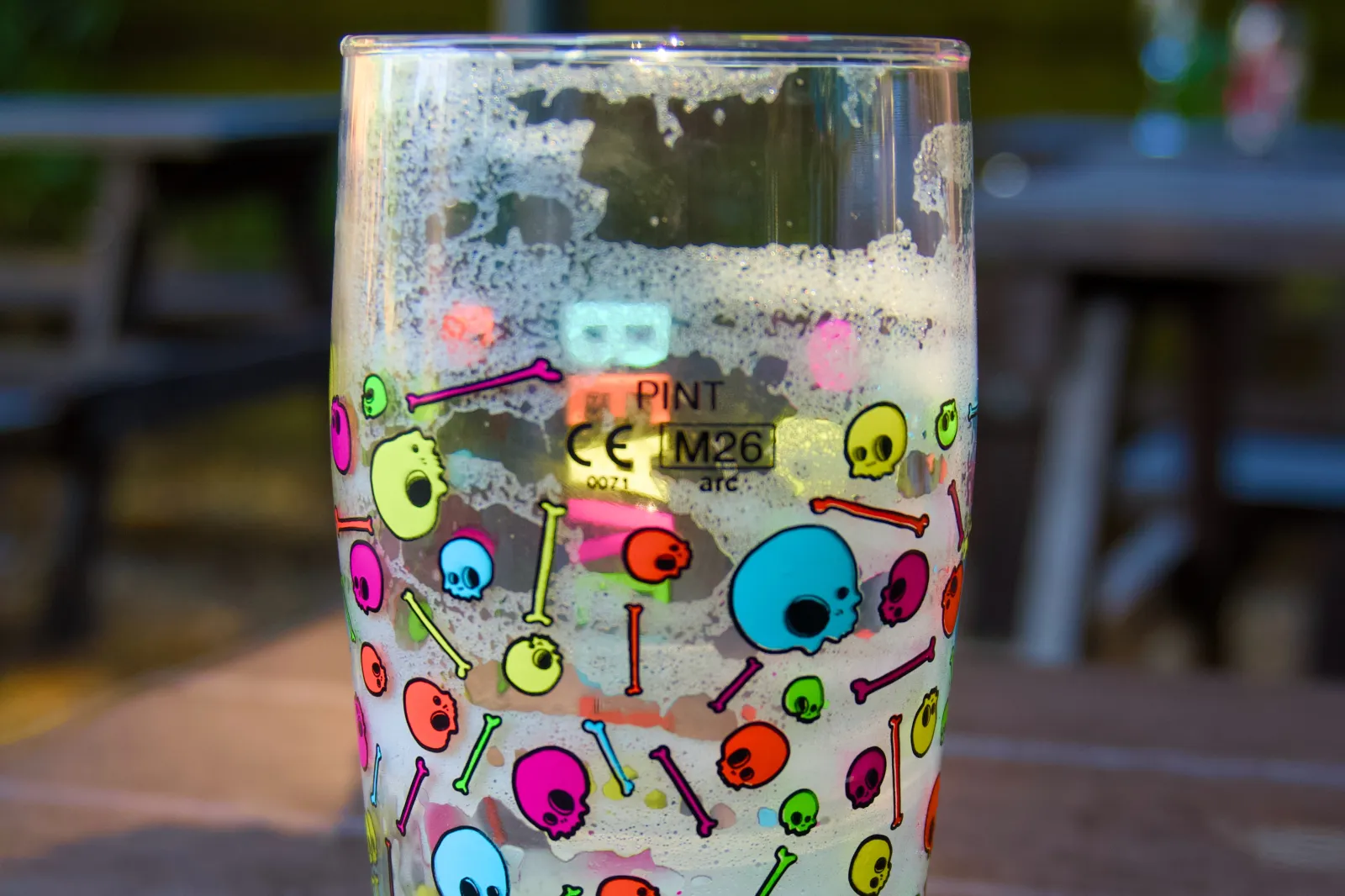 Empty pint glass printed with colorful skulls and bones