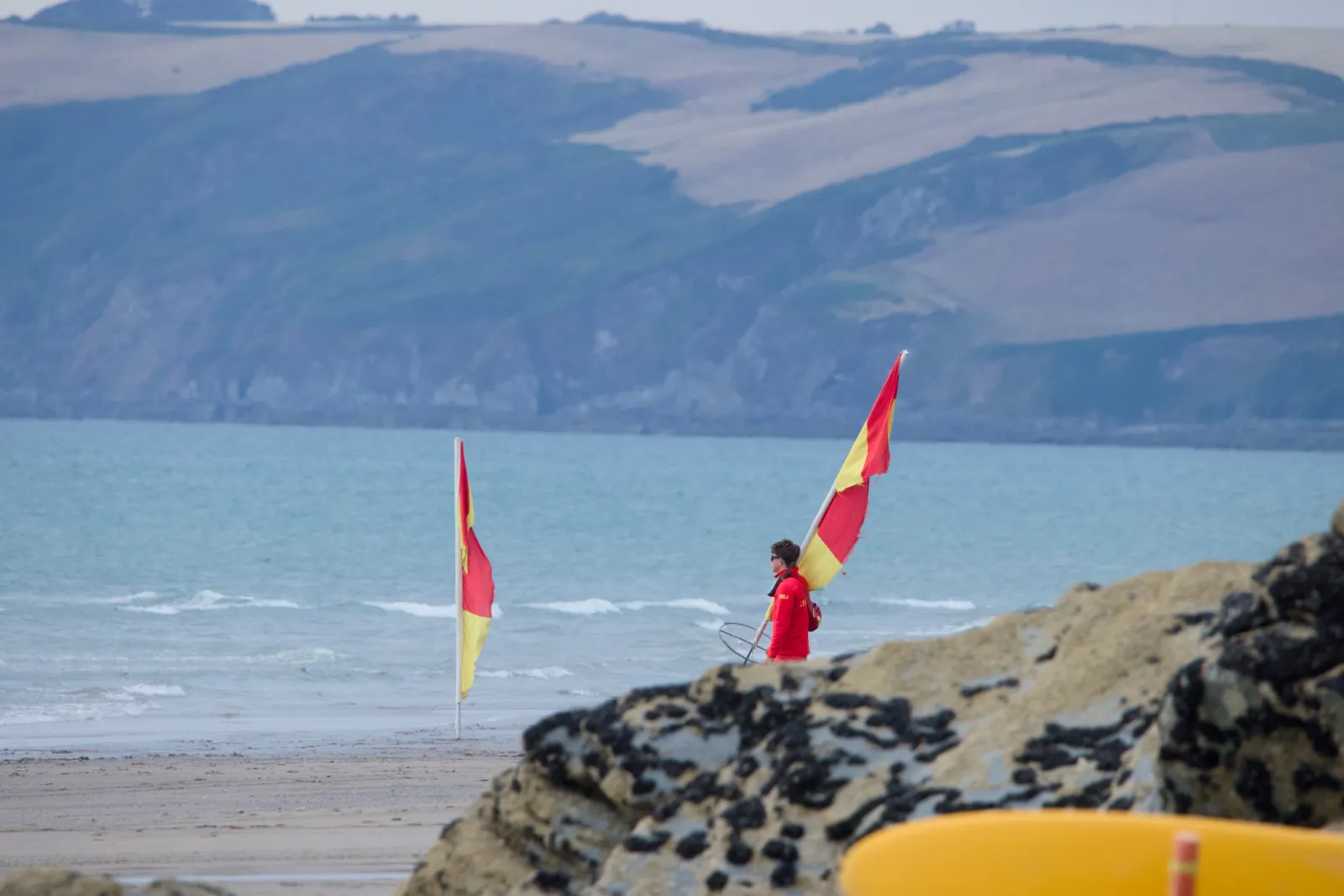 Lifeguard carrying the red and yellow flags off the beach