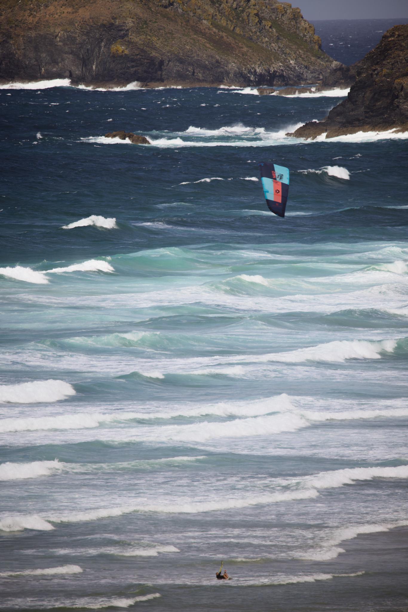 Kitesurfer's kite over the waves in front of the cliffs