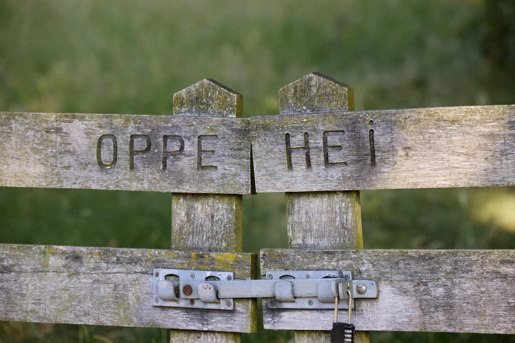 Weathered wooden gate with Oppe Hei carved into it