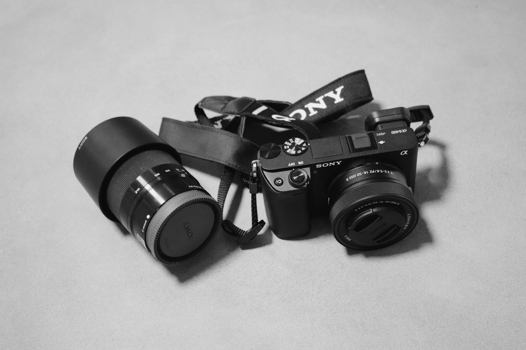 Sony Alpha 6400 with kit lens and a second telephoto lens next to it, in black and white