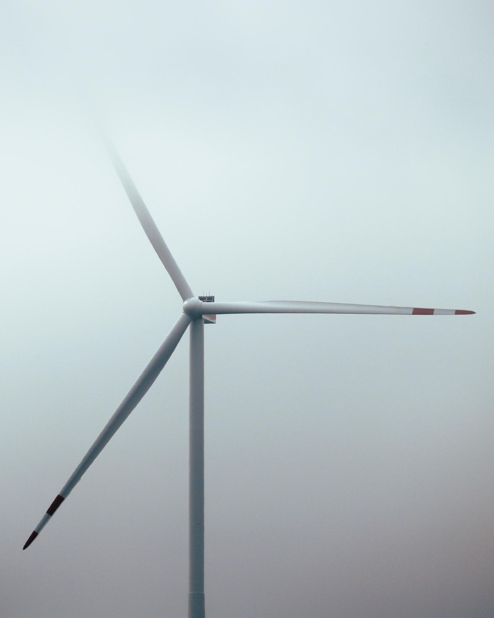 Wind turbine dissolving into a grey misty sky