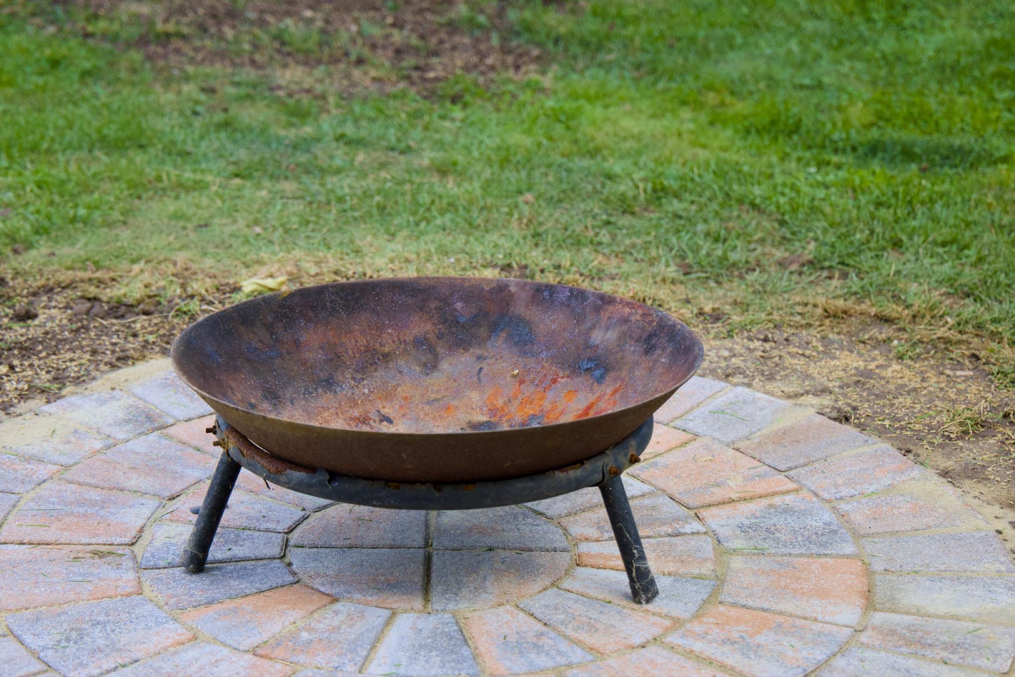Rusty fire bowl on a paved circle in the lawn