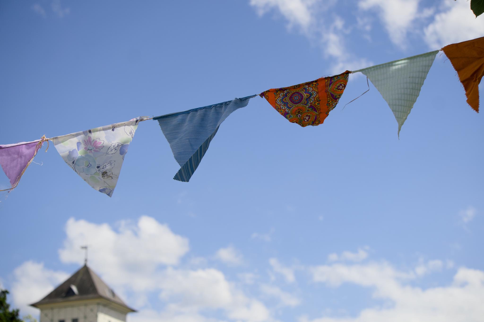Colourful fabric bunting against a blue sky, a tower in the corner