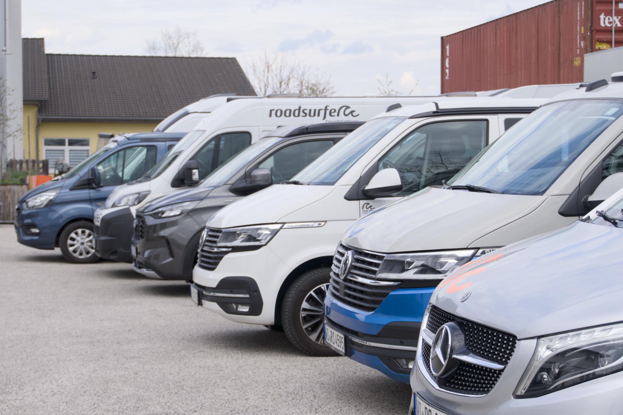 A row of campervans parked side by side at a roadsurfer station